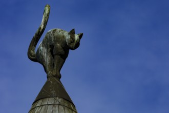 Detail of the cat house roof in Riga with a cat as a sculpture against the blue sky, Riga, Latvia