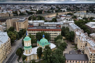 Annunciation of Our Lady in the midst of municipal buildings and green tree roofs, Riga, Latvia