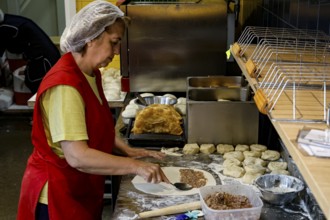 A woman prepares fresh chebureks at a stand at the Central Market in Riga, Riga, Latvia