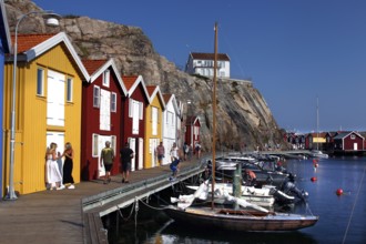Lively harbor scene with colorful boathouses and walkers along the promenade, Smögen, Västra