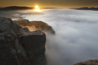 The rising sun paints dramatic colors over the sea of clouds at Preikestolen, Preikestolen,