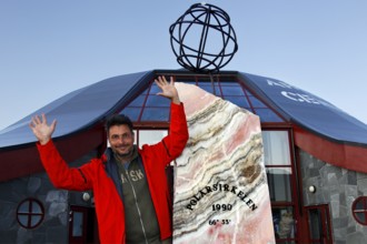 Happy person in front of the distinctive symbol of the Arctic Circle, zero