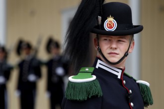 Norwegian security guard in decorative uniform wearing a hat decorated with feathers in front of