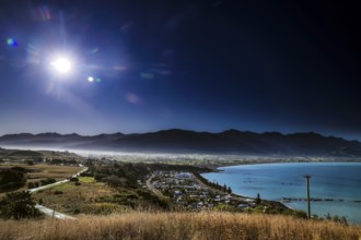 Extensive view of Kaikoura with mountains and sea under bright skies, zero