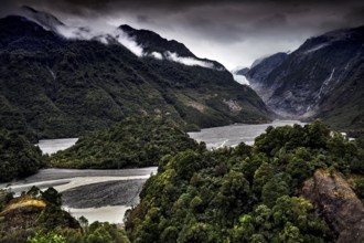 Franz Josef glacier stretches through a wooded valley under an ominous sky, Franz Josef, West