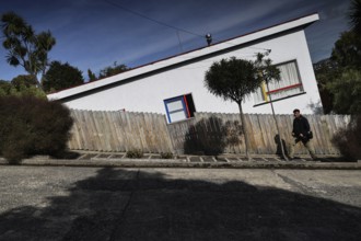 Steep slope of a road with a white house and trees in the background in Dunedin, Dunedin, Otago,