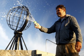 Man spraying globe sculpture at North Cape against clear sky, North Cape, Norway