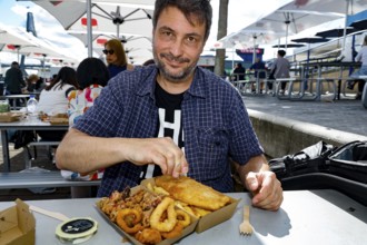Man enjoying fish and squid rings outdoors at Sydney Fish Market, Sydney, New South Wales,