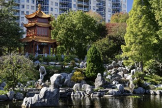Temple surrounded by rocks and plants with city buildings in the background, Sydney, New South