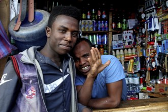 Two men stand in front of a well-equipped shop at a local market, Awaday, Afar, Ethiopia