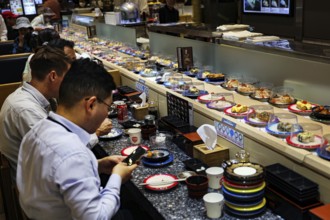 Sushi on an assembly line in the busy food court of a department store, Busan, South Korea