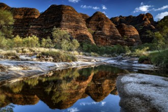 Dramatic rocky landscape reflected in the clear water of a waterhole, Purnululu National Park,