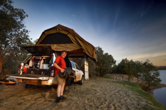 A riverside camp with roof tent and vehicle, surrounded by dusk, Pentecost River, Western