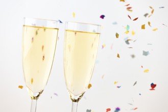 Two champagne glasses with colorful confetti in the background