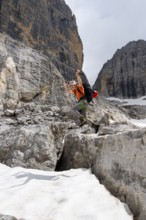 Mountaineer jumping off a rock into the snow, Camosci Valley, Brenta Mountains, Brenta-Adamello
