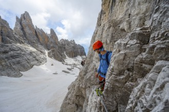 Mountaineer climbs on a steep rock face in the Via Ferrata dell'Ideale via ferrata, spectacular