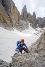 Mountaineer climbs on a steep rock face in the Via Ferrata dell'Ideale via ferrata, spectacular