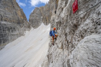 Mountaineer climbs on a steep rock face in the Via Ferrata Brentari via ferrata, spectacular