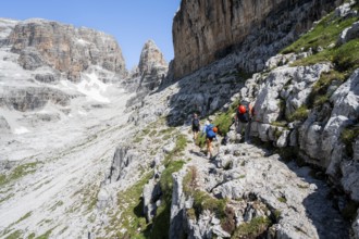 Three mountaineers on a hiking trail to Sella della Tosa, mountainous landscape in the Brenta