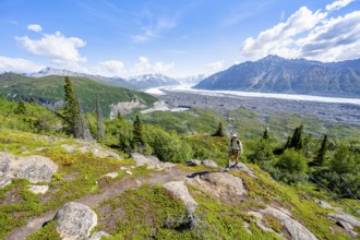 Young man on a hiking trail, view of impressive mountain landscape with Matanuska glacier and