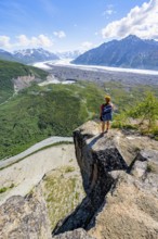 Young woman on a rocky outcrop enjoying the view, view of impressive mountain landscape with
