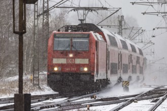 RegionalExpress RE on the road through a winter landscape in snowfall. A train on the line in the