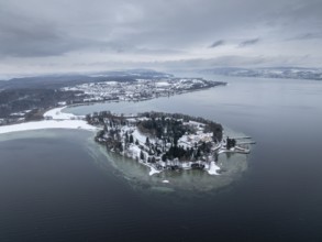 The wintry and snowy Mainau island in Lake Constance with the pier and the baroque Mainau Castle,