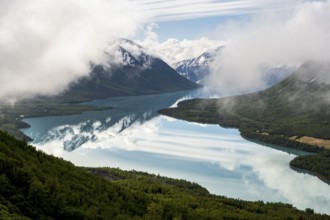 View of snowy mountains in spring and turquoise Kenai Lake with reflection, Slaughter Ridge Trail,