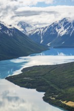 View of snowy mountains in spring and turquoise Kenai Lake with reflection, Slaughter Ridge Trail,