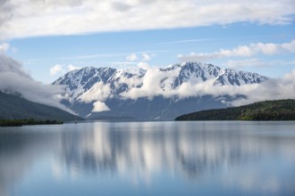 Snowy mountains in spring are reflected in turquoise blue Kenai Lake, Cooper Landing, Kenai