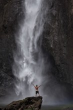 Daytime scene at Wallaman Falls with a fit man in swim trunks below the waterfall, Queensland,