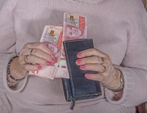 An elderly woman's hands take out Swedish banknotes from a wallet