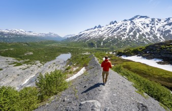 Hikers on glacial moraine, view of the vast Tsina River valley with mountains, Worthington Glacier