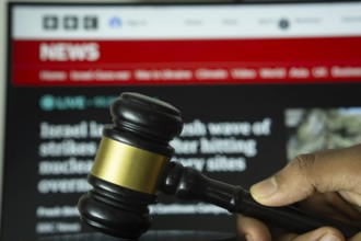 Dhaka, Bangladesh- 20 June 2025: A hand holds a gavel in front of a computer screen displaying