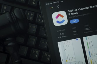 Dhaka, Bangladesh- 28 Oct 2025: An iPad displaying the ClickUp app against a judge's gavel and dark