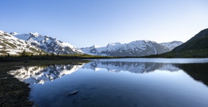 Mountain peaks with Portage Glacier glacier and snow reflected in Divide Lake mountain lake in