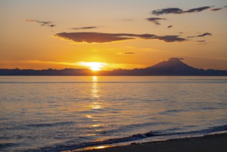 View of Cook Inlet on white mountain peaks of Mount Redoubt at sunset, picturesque golden light of