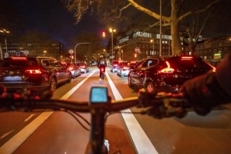 Cycling in the city, in the dark, in the evening, cycling on a bike lane, marked in red,