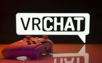 Dhaka, Bangladesh- 14 Nov 2025: A close-up of a white gamepad with the VRChat seen on screen in the