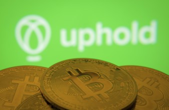 Dhaka, Bangladesh- 19 Sep 2025: Close-up of Bitcoin coins with the Uphold logo visible on a screen