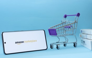 Dhaka, Bangladesh- 21 Nov 2025: Smartphone with amazon marketplace logo next to a small shopping