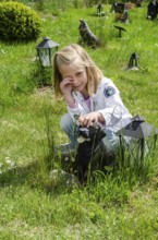 Grieving blonde 7-year-old girl at her dog's grave at pet cemetery in Ystad, Skåne County, Sweden,