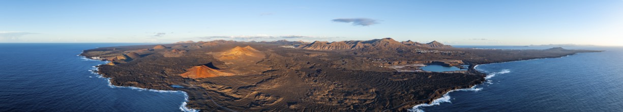 Coast with lava fields, volcanic landscape near Los Hervideros with red volcano Montaña Bermeja, in