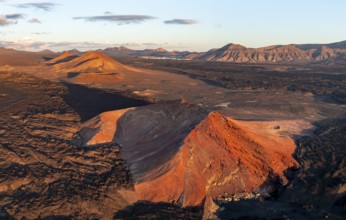 Picturesque volcanic landscape in evening light, red volcano Montaña Bermeja between lava fields,