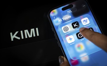 In this photo illustration, a person uses the Kimi AI chatbot on a smartphone while the KIMI logo