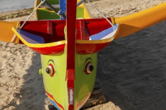 Colourfully painted outrigger fishing boats, (Junkung), on Sanur beach, Bali, Indonesia