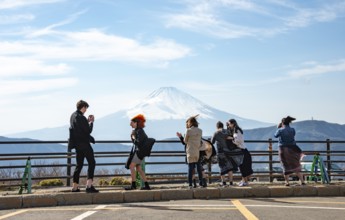 Tourists enjoy the view and take pictures, view of the snow-covered summit of Mount Fuji volcano in