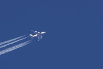 Airbus A380 jet passenger aircraft of Emirates airlines flying in a blue sky with contrails or