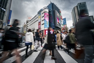 Crowd crossing zebra crossing on a large intersection, motion blur, back modern houses with
