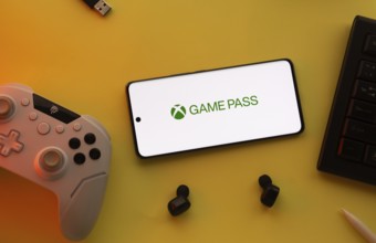 Dhaka, Bangladesh- 15 July 2025: Smartphone with Xbox game pass logo, game controller, and earbuds